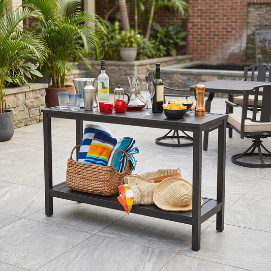 Weatherproof black aluminum outdoor console table used as BBQ prep serving table for backyard gathering