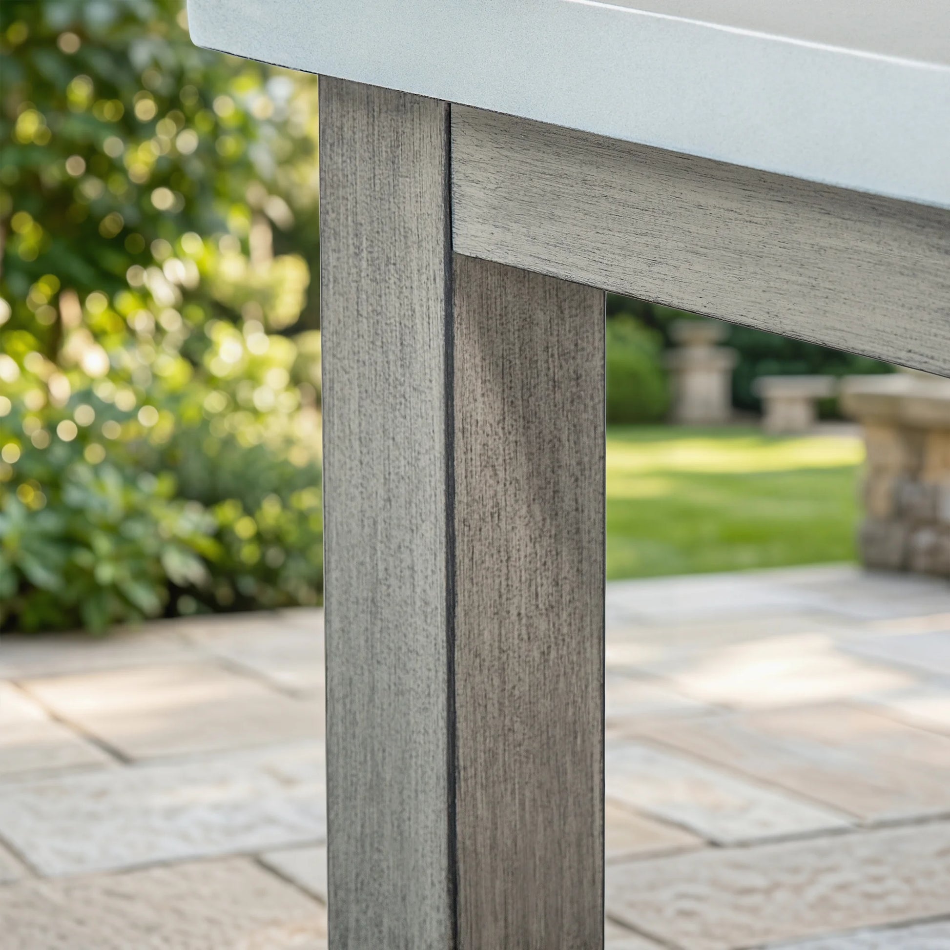 Close-up of a wood-look outdoor table leg with a blurred garden background
