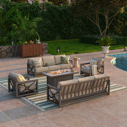 An upscale open-air salon by a pool at sunset, displaying the Marindo 8-guest aluminum patio set with a glowing fire pit centerpiece throwing warm light onto the surrounding sofas and swivel accent chairs.